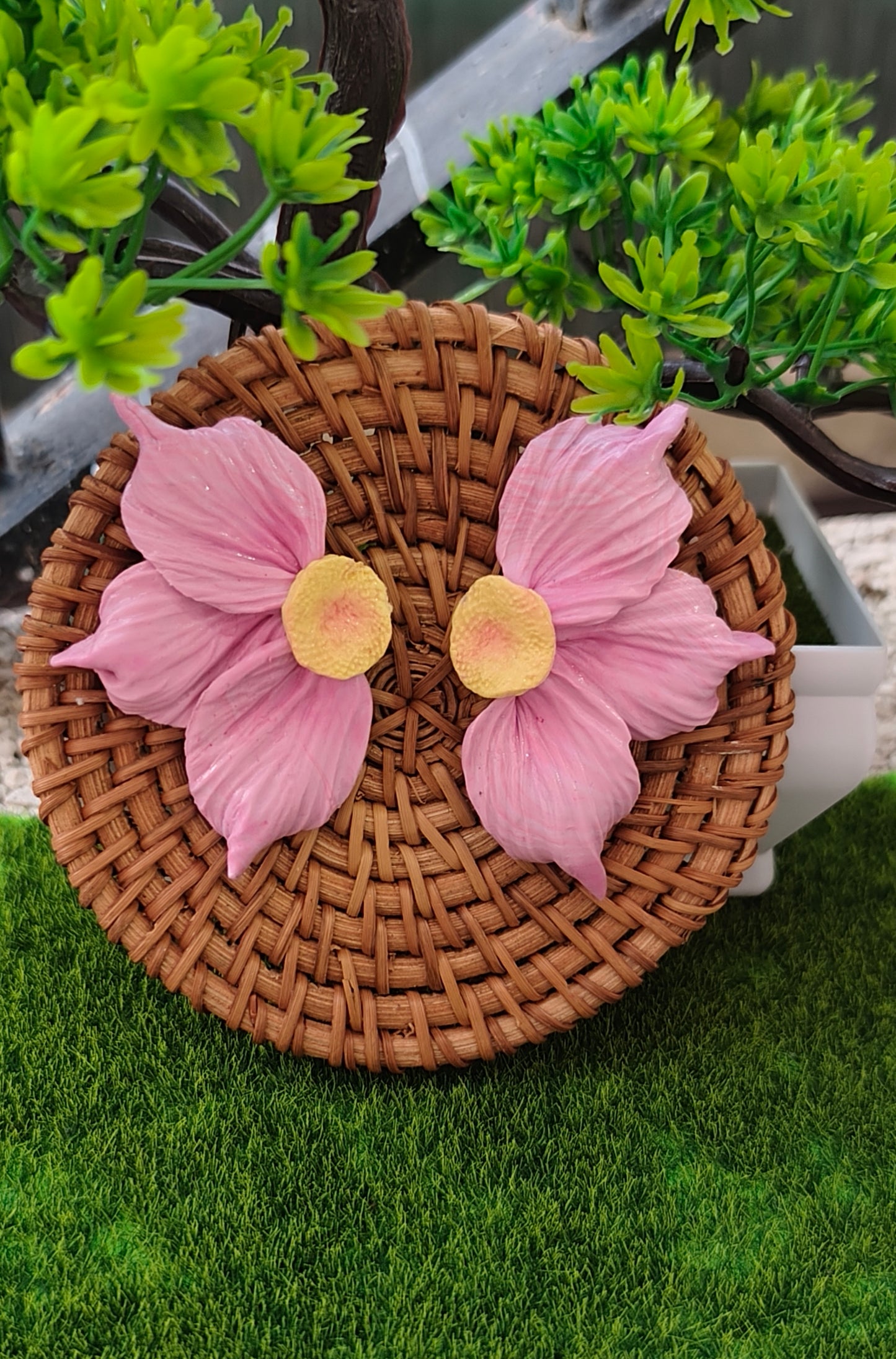 Pendientes maxi flor rosa sobre cesto de mimbre con plantas