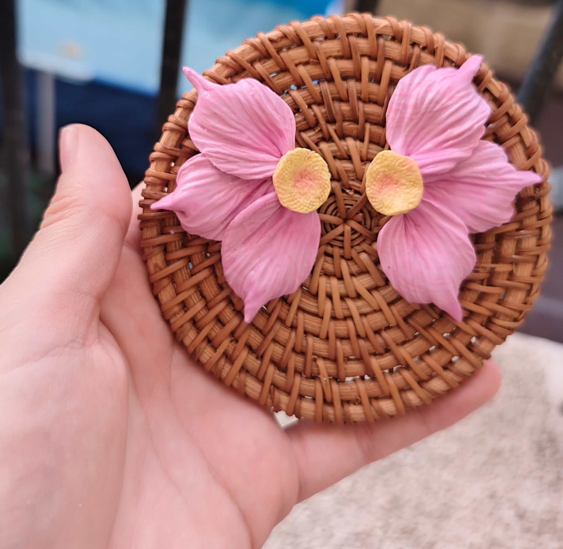 Pendientes maxi flor rosa sobre cesto de mimbre en mano