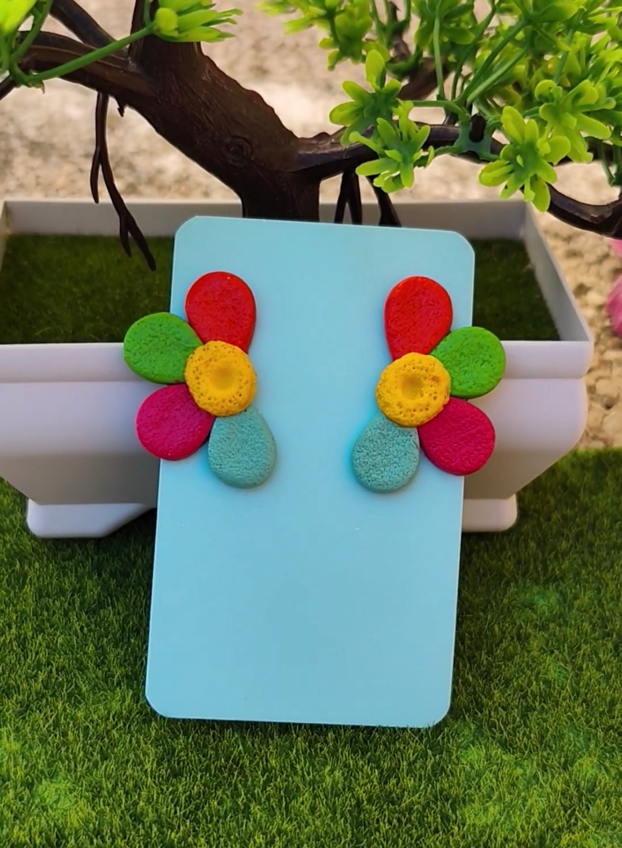 Pendientes flor multicolor sobre tarjeta azul